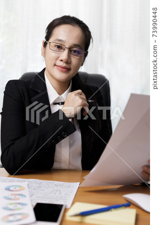 Business women smileing wear glasses holding document paper chart sitting at office. business people using computer PC  at office. Business at home concept. 73990448