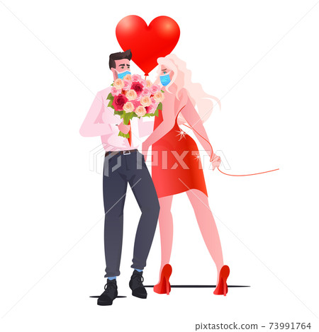 man woman in masks standing together couple celebrating valentines day coronavirus quarantine concept 73991764