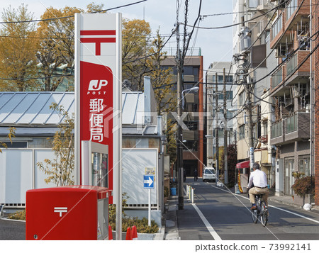 Japan post office in Tokyo city. Urban lifestyle with people riding bicycle on street Japan post office in Tokyo city. Urban lifestyle with people riding bicycle on street 73992141
