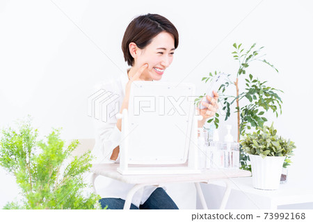 看著她的智能手機做皮膚護理的中年女人 73992168