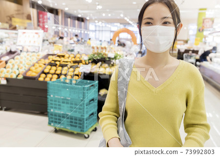 戴著面具在一家超市購物的女性顧客 73992803