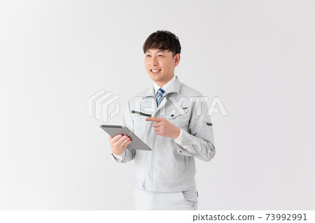 Young worker talking while looking at a tablet on a white background Young worker talking while looking at a tablet on a white background 73992991