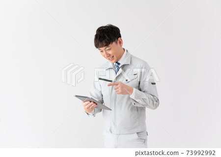 Young worker talking while looking at a tablet on a white background Young worker talking while looking at a tablet on a white background 73992992