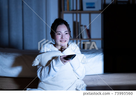 Young woman watching tv at night Young woman watching tv at night 73993560