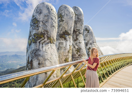 Young woman tourist at Famous tourist attraction - Golden bridge at the top of the Ba Na Hills, Vietnam 73994651