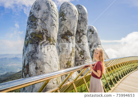 Young woman tourist at Famous tourist attraction - Golden bridge at the top of the Ba Na Hills, Vietnam 73994653