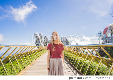 Young woman tourist at Famous tourist attraction - Golden bridge at the top of the Ba Na Hills, Vietnam 73994654