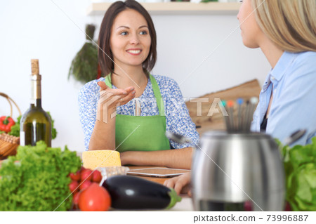 Two young happy woman making cooking in the kitchen. Friendship and culinary concept 73996887