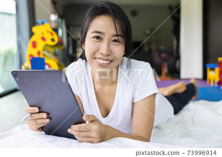 woman using digital tablet in a bed at home. The use of concept of new generation, family, parenthood, authenticity, connection, technology. 73996914