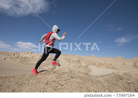 Woman trail runner cross country running on sand desert dunes Woman trail runner cross country running on sand desert dunes 73997164
