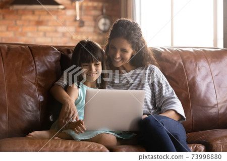 Close up happy mother and little daughter hugging, using laptop Close up happy mother and little daughter hugging, using laptop 73998880
