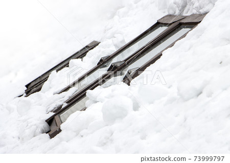 The snowy roof with windows of the house. Sunroofs in winter. The snowy roof with windows of the house. Sunroofs in winter. 73999797