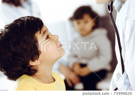 Woman-doctor examining a child patient by stethoscope. Cute arab boy at physician appointment. Medicine help concept 73999820