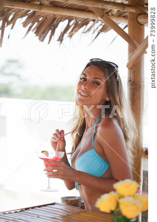 Woman drinking cocktail on beach bar 73999828