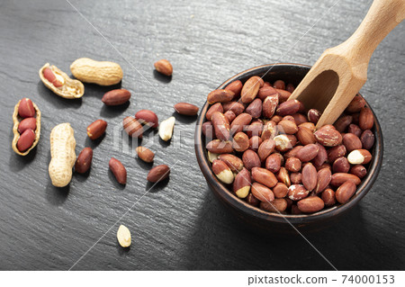 Peeled peanuts in a bowl on a black table. Product for making peanut butter or butter. Beer snacks. Peeled peanuts in a bowl on a black table. Product for making peanut butter or butter. Beer snacks. 74000153