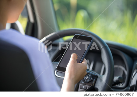 Woman driver using smartphone while driving a off road car in the nature Woman driver using smartphone while driving a off road car in the nature 74000907