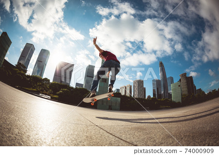 Asian woman skateboarder skateboarding in modern city 74000909