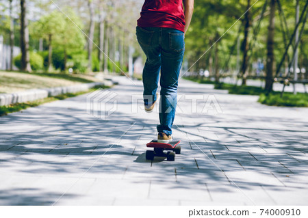 Asian woman skateboarder skateboarding in modern city Asian woman skateboarder skateboarding in modern city 74000910