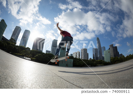Asian woman skateboarder skateboarding in modern city Asian woman skateboarder skateboarding in modern city 74000911