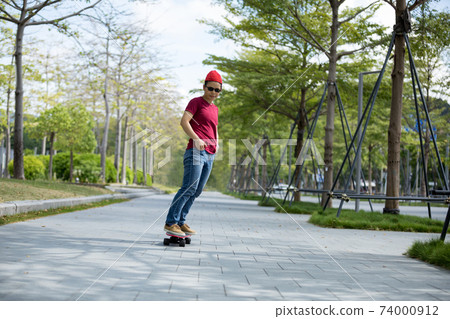 Asian woman skateboarder skateboarding in modern city Asian woman skateboarder skateboarding in modern city 74000912