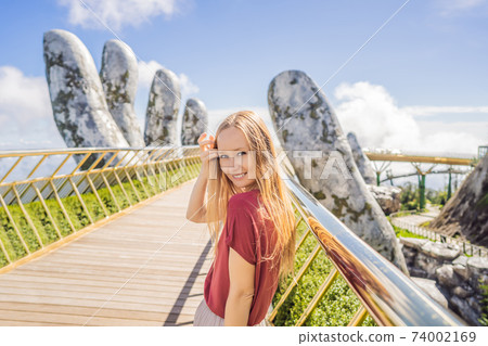 Young woman tourist at Famous tourist attraction - Golden bridge at the top of the Ba Na Hills, Vietnam Young woman tourist at Famous tourist attraction - Golden bridge at the top of the Ba Na Hills, Vietnam 74002169