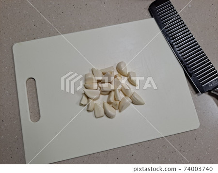 Peeled garlic and knife on a cutting board Peeled garlic and knife on a cutting board 74003740