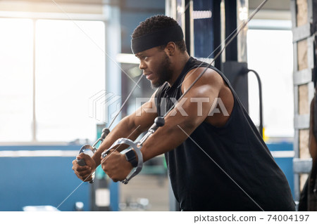 Young black sportsman training triceps on block exerciser in gym Young black sportsman training triceps on block exerciser in gym 74004197