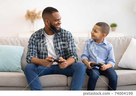 Happy Black Daddy And Son Playing Video Games At Home 74004199