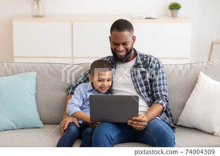 Happy Black Father And Son Using Tablet Sitting At Home Happy Black Father And Son Using Tablet Sitting At Home 74004309