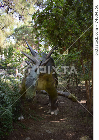 Dinosaur statue in the forest park in nature for background. Stegosaurus, replicas of a dinosaurs in natural size reconstructed Dinosaur statue in the forest park in nature for background. Stegosaurus, replicas of a dinosaurs in natural size reconstructed 74004356
