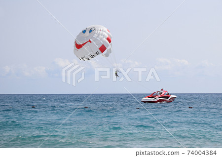 Funny parasail wing pulled by a boat. Sea summer recreation. Summer water beach extreme sports. 74004384