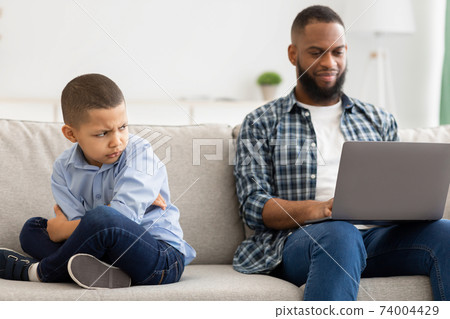 Indifferent Black Father Neglecting Son Using Laptop Sitting At Home Indifferent Black Father Neglecting Son Using Laptop Sitting At Home 74004429