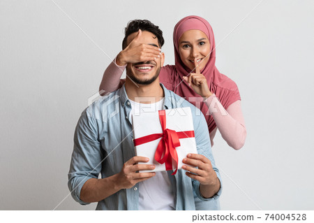 Surprise Gift. Romantic Muslim Woman Covering Her Husband's Eyes And Giving Present 74004528