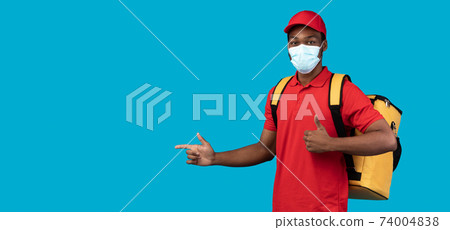 African american delivery man in mask pointing at copy space 74004838
