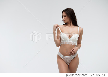 Hot sexy woman in white lace lingerie looking at camera touching body Hot sexy woman in white lace lingerie looking at camera touching body 74005151