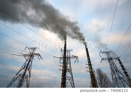 High voltage power lines and coal power plant pipes with black smoke moving up polluting atmosphere. High voltage power lines and coal power plant pipes with black smoke moving up polluting atmosphere. 74006133