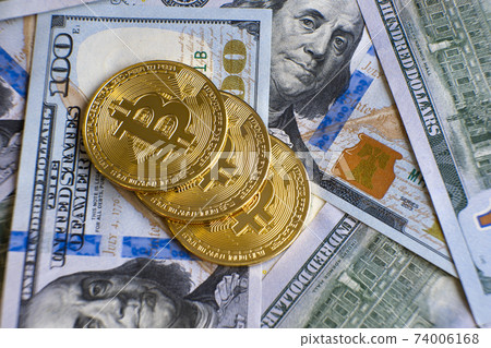 Close up of metal shiny bitcoin crypto currency coins on US dollar bills. Electronic decentralized money concept. 74006168