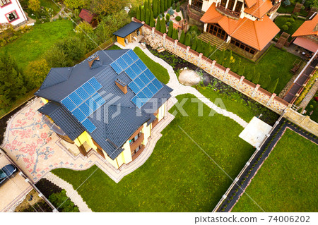 Aerial view of a private house with solar photovoltaic panels for producing clean electricity on roof. Autonomous home concept. Aerial view of a private house with solar photovoltaic panels for producing clean electricity on roof. Autonomous home concept. 74006202