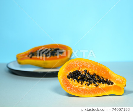 Two Half of Papaya with Seeds on Blue Background, Minimalism Trendy Food, Healthy and Detox Eating, Raw lunch, Copyspace, Exotic Fruit Two Half of Papaya with Seeds on Blue Background, Minimalism Trendy Food, Healthy and Detox Eating, Raw lunch, Copyspace, Exotic Fruit 74007193