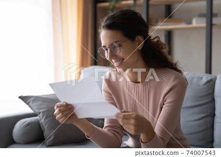 Happy young woman in glasses reading paper letter. Happy young woman in glasses reading paper letter. 74007543
