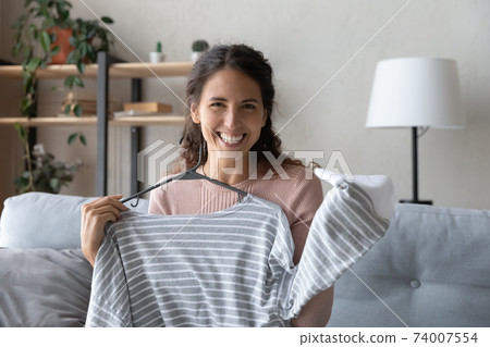 Gadget screen view happy young female influencer showing clothes. 74007554