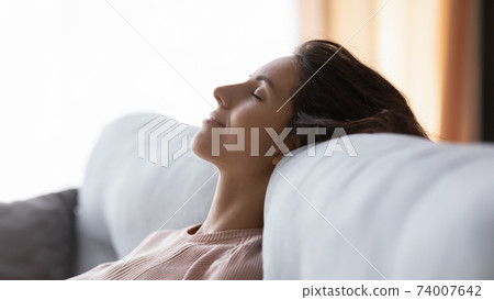 Tranquil young pretty woman sleeping on comfortable couch. 74007642