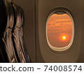 Big sun at sunset sky from airplane window. Travelling by airplane seat near window enjoying beautiful sunset. Sunset through aircraft window. 74008574