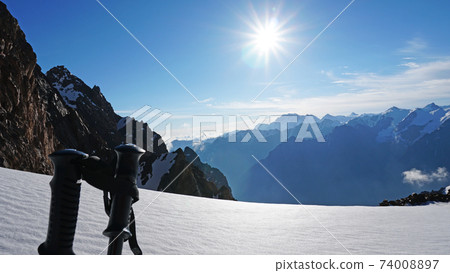 Trekking sticks on the background of snow peaks. Trekking sticks on the background of snow peaks. 74008897