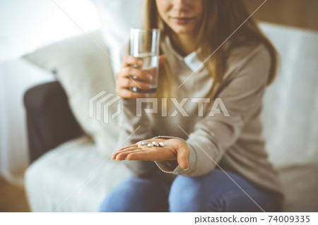 Close-up woman holding pills time to take medications, cure for headache, high blood pressure or cholesterol level remedy pain killer drugs. Stay at home concept during Coronavirus pandemic and self 74009335