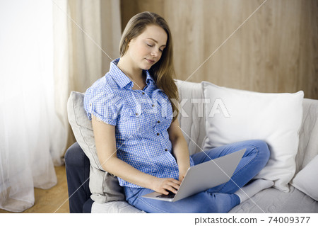 Businesswoman working on laptop computer sitting indoors during Covid-19 quarantine. Stay at home concept during Coronavirus pandemic Businesswoman working on laptop computer sitting indoors during Covid-19 quarantine. Stay at home concept during Coronavirus pandemic 74009377