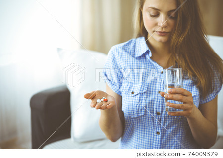 Close-up woman holding pills time to take medications, cure for headache, high blood pressure or cholesterol level remedy pain killer drugs. Medicine concept 74009379