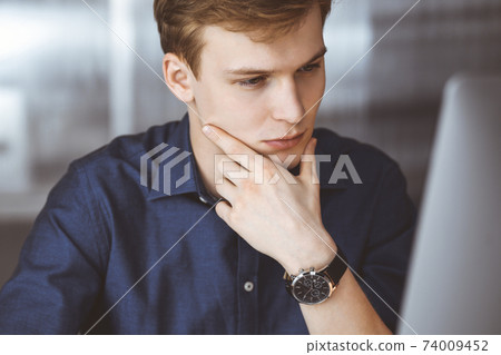 Young blond businessman feeling stress at workplace in office. Startup business means working hard and out of time for success achievement Young blond businessman feeling stress at workplace in office. Startup business means working hard and out of time for success achievement 74009452