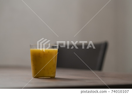 Mango lulo smoothie on walnut wood table with copy space 74010107