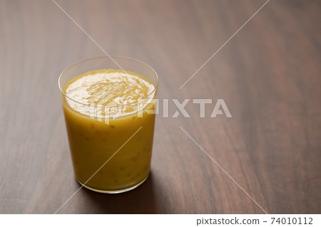 Mango lulo smoothie on walnut wood table with copy space 74010112